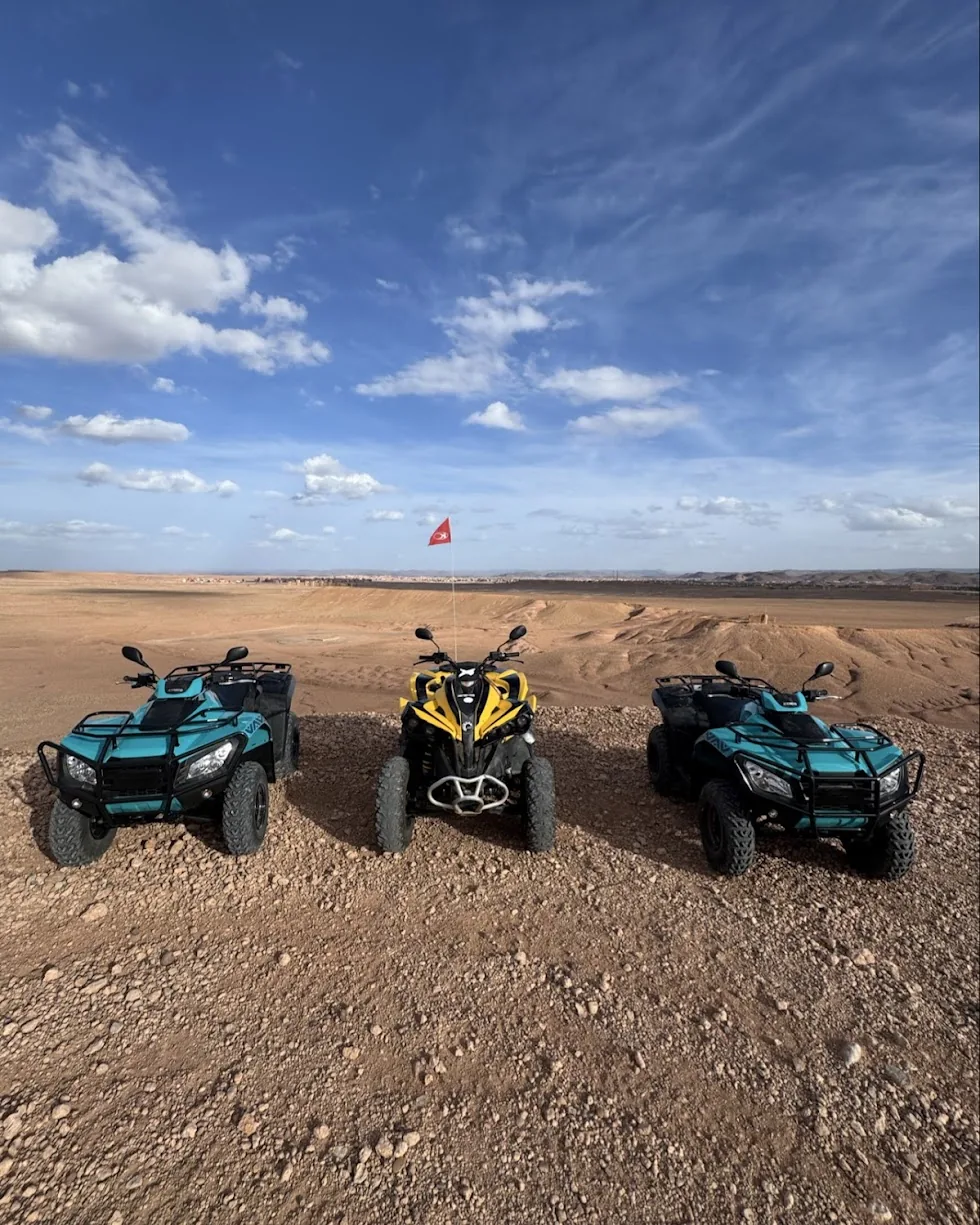 Three turquoise and yellow GoSahara quad bikes overlooking rocky desert hills