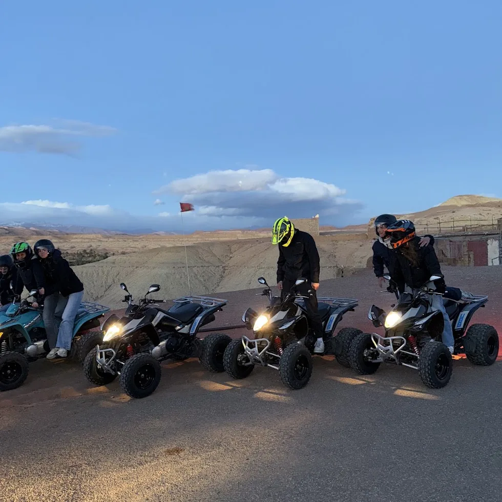 Helmeted riders on quad bikes lined up beside rocky hills